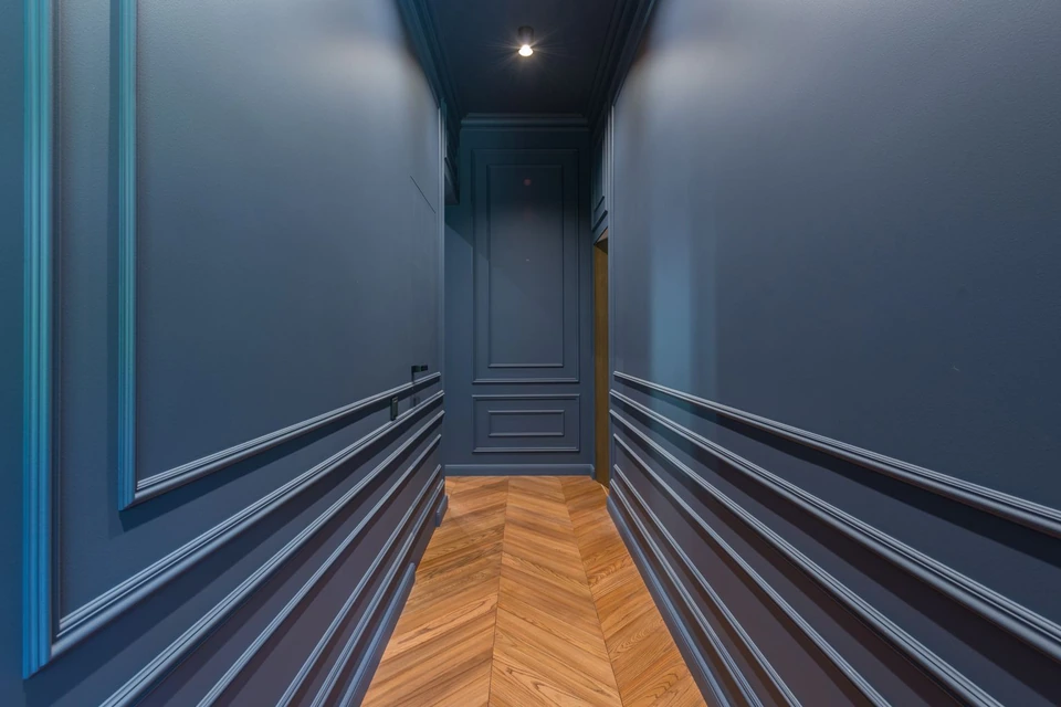 Couloir aux murs bleus moulurés et au parquet en point de Hongrie
