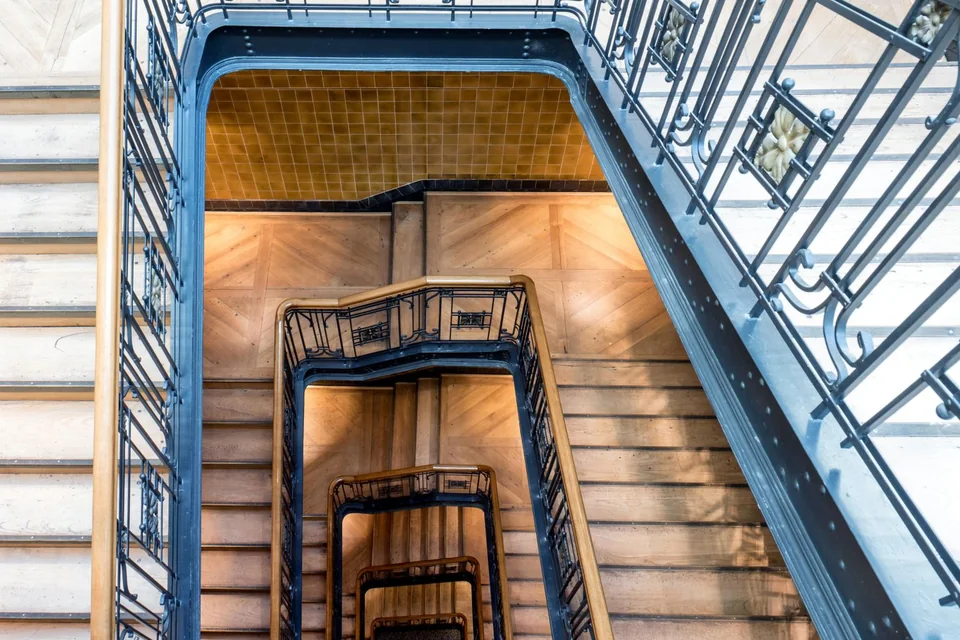 Escalier d'immeuble à rampe métallique bleue vu du palier supérieur