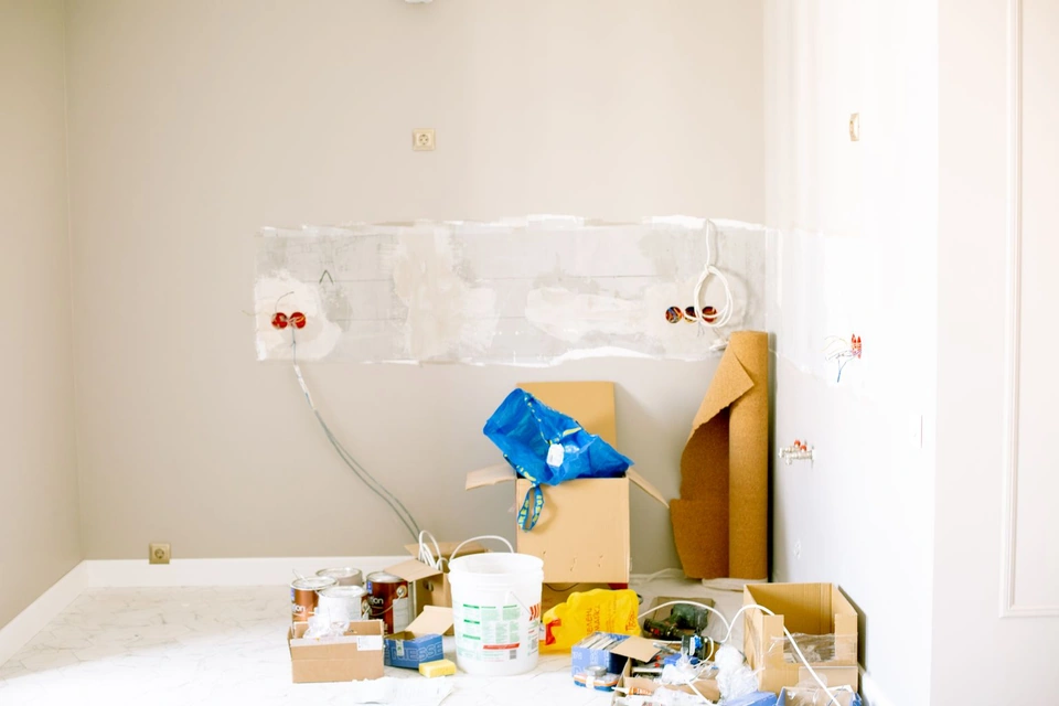 Pièce en rénovation avec cartons, pots et outils au sol